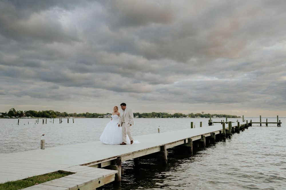 A dramatic panoramic view of a wooden pier stretching into a moody lake under stormy cloudy skies in Baltimore MD