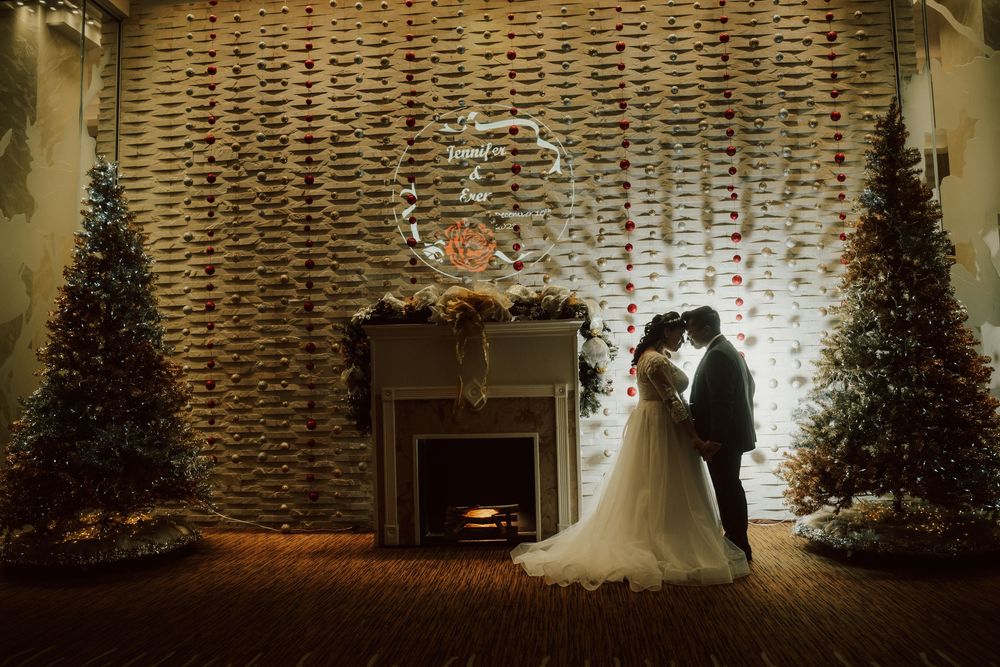 Christmas trees and string lights create a festive holiday backdrop for a winter wedding ceremony.